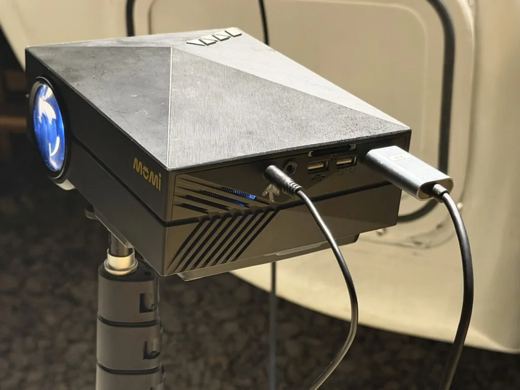 投影機側邊右側銀色轉接頭接在 HDMI 影像輸入，左側黑色圓頭線接在 3.5 mm 音源輸出