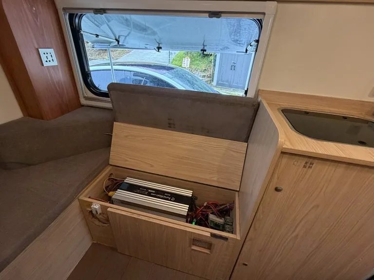 露營車流理台旁右側座椅掀開後，可看到座椅下方的銀色逆變器