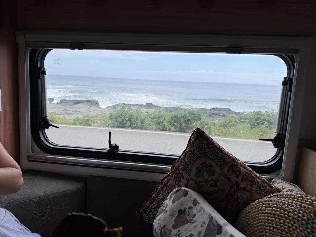 Ocean waves seen through the campervan window during a quiet morning inside the vehicle