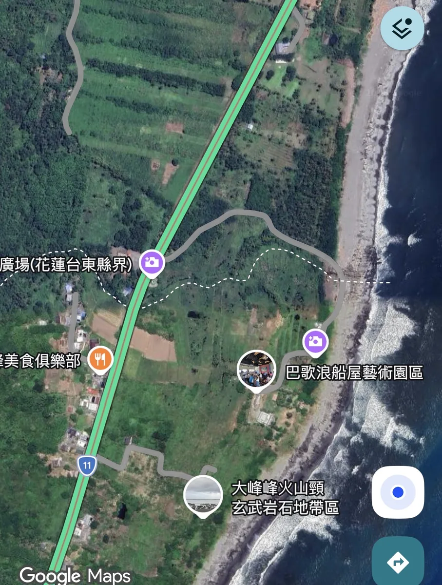 Google Maps satellite view showing coastline, fields, a main road and a minor road near the sea